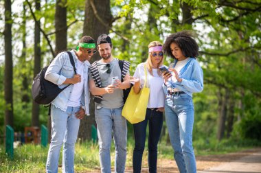 Otostopçular. Genç turistler orman yolunda otostop çekiyorlar.