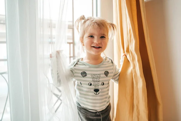 Smiling Happy Cute Little Girl Ponytails Standing Curtains Looking Her — Stock Photo, Image