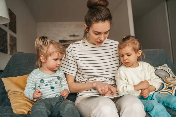 Joven Madre Sentada Sofá Señalando Imagen Libro Sus Lindos Hijos —  Fotos de Stock