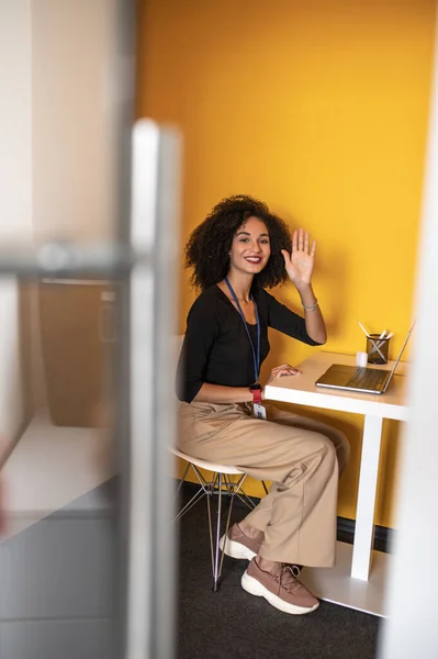 Greeting. Cute dark-haired woman greeting her coworker and smiling