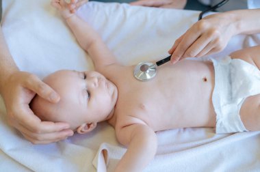 Kalp kontrolü. Pediyatrist steteskopla bebeğin kalp ritmini dinliyor.