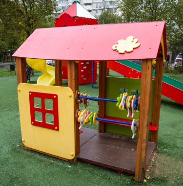 Açık güneşli bir günde ahşap tezgahlı parlak sarı ve kırmızı renkli ahşap bir ev-veranda. Oyun alanları, spor, sağlık eğlencesi.