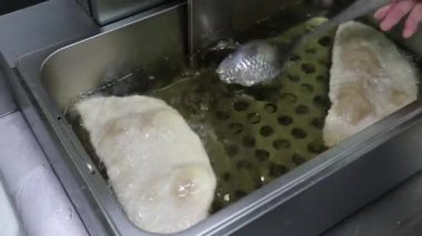 Kızgın yağlı, kızgın yağlı metal bir kapta hamur tatlısı kızartıyorlar. Ulusal fırın ürünleri geleneksel yemek ve hamur işleri.