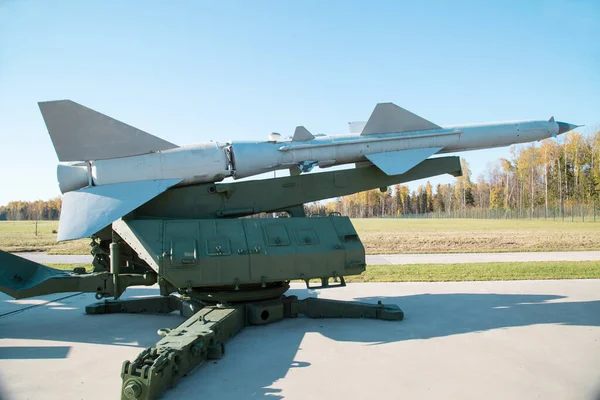 Bir ormanın arka planında fırlatıcı ve mavi gökyüzü olan gümüş renkli bir roket. Askeri teçhizat füze helikopterleri.