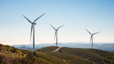 Sardunya 'daki bir dağ rüzgâr çiftliğinde güzel mavi bir gökyüzünde rüzgar türbinleri. Yenilenebilir enerji konsepti, yeşil enerji üretimi. Enerji endüstrisi.