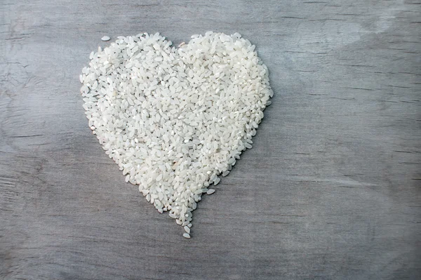 Grains de riz formés en forme de coeur sur fond de bois — Photo