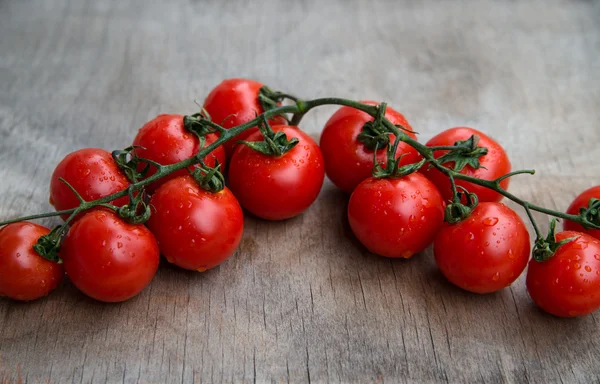 Веточка свежих красных вкусных помидоров черри на старом деревянном столе — стоковое фото