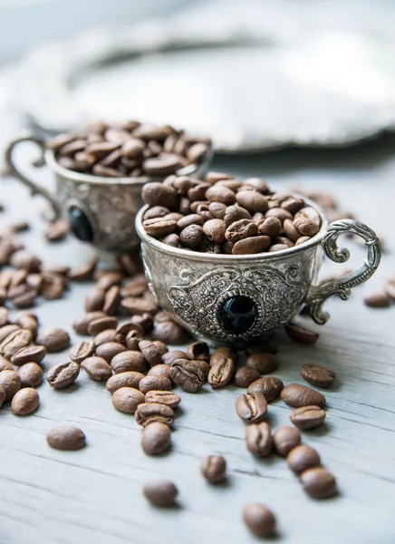 Granos de café en tazas vintage de plata sobre fondo de madera — Foto de Stock