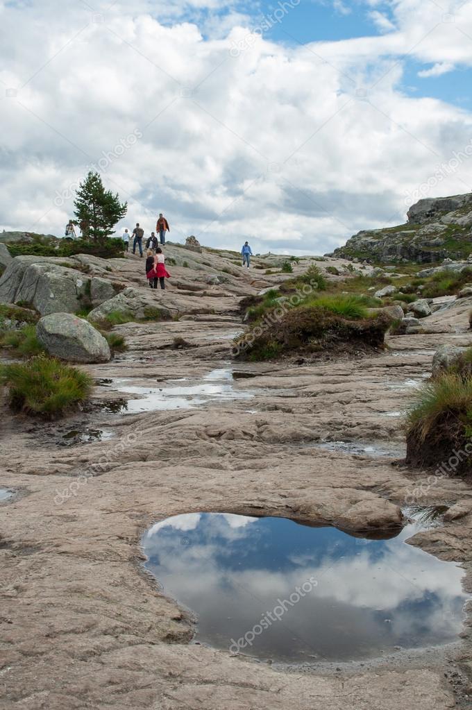 tourists walk along the way to Preikestolen in the mountains in 