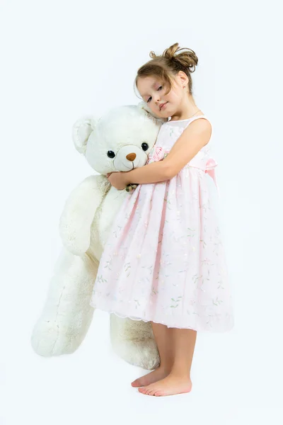 Cute girl in pink dress hugs big white bear on light background — Stock Photo, Image
