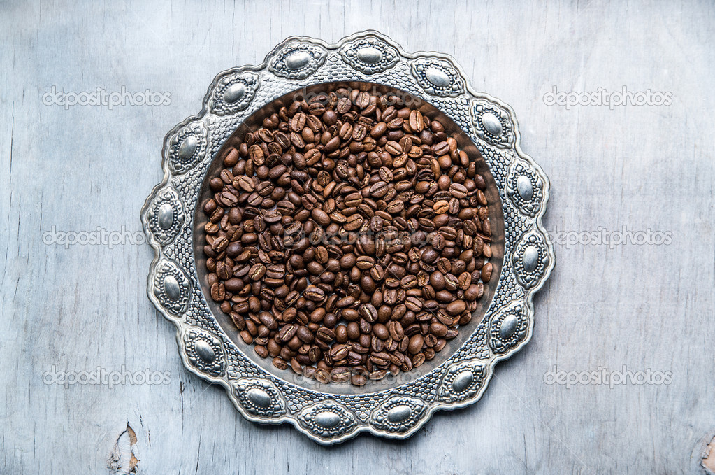 Coffee beans in silver vintage plate on wooden background