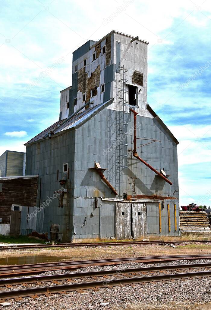 An old neglected grain elevator adjacent to unused railroad tracks reflect memories of yesterday