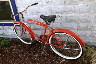 Eski bir kırmızı pedallı çocuk bisikleti. Tuğla bir binaya park ettim.. 