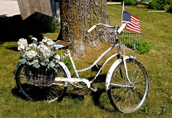 古い白い女の子の自転車は花のバスケットとアメリカの国旗で飾られています — ストック写真