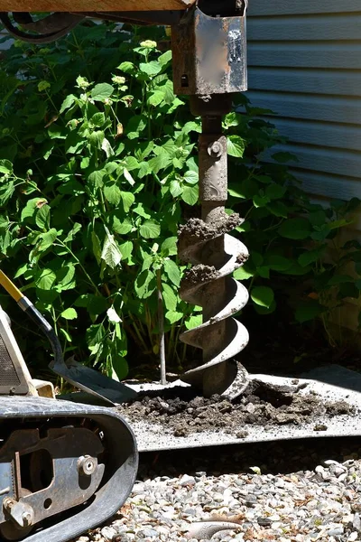 ホームを持つ家の隣に穴を掘り土を集めるオーガー — ストック写真