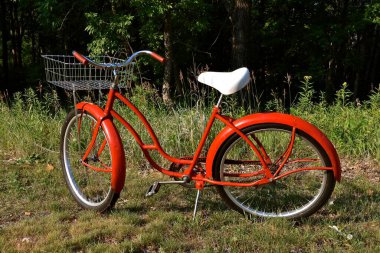 An old red bicycled has been re-conditioned  including a new white seat. 