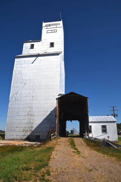 The abandoned elevator grain truck drive through is partially torn down exposing a steel grain bin on the distance.
