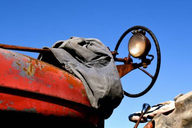 Eski bir kırmızı traktörün operatörü direksiyonun başına bir ceket bırakmış.. 