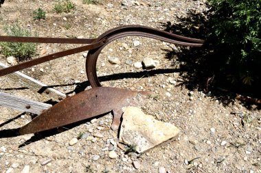 A very old and simple one bottom plow serves a as decoration in a rock and flower garden