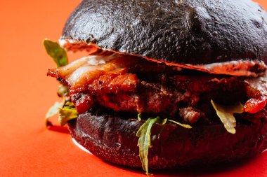 Siyah çörekler ızgara et burger, peynirli ve domatesli kırmızı arka plan. 