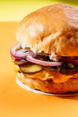 Arka planda sosisli ve peynirli hamburger.