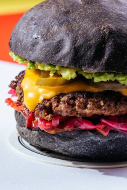 Siyah çörekler ızgara et burger, peynirli ve domatesli kırmızı arka plan. 