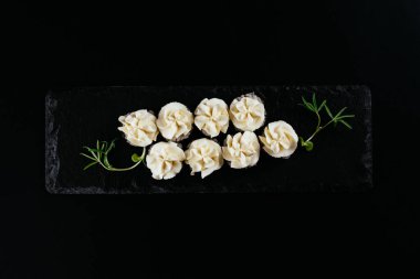 Siyah arkaplanda beyaz mayonez ile servis edilen suşi ruloları. 