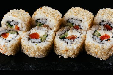 Siyah arka planda servis edilen suşi ruloları. 