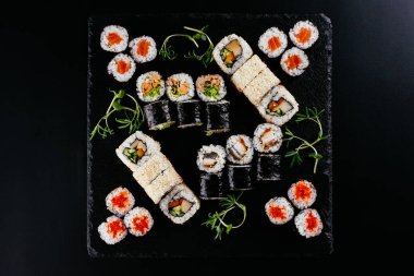Siyah arka planda Japon suşi ruloları olan farklı bir set.