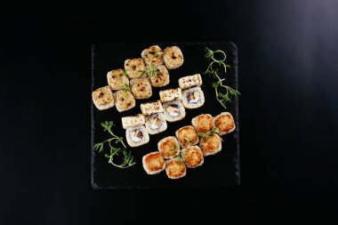 Siyah arka planda Japon suşi ruloları olan farklı bir set.