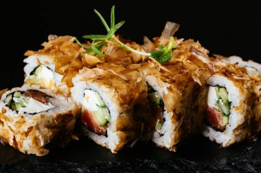 Siyah arka planda somon, avokado, salatalık ve zencefilli suşi..