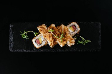 Somonlu suşi ve siyah arka planda avokado.