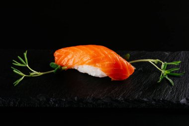 Deniz mahsullü nigiri suşi ve siyah arka planda pirinç.