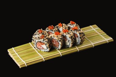 Somonlu suşi ve siyah arka planda sebze.