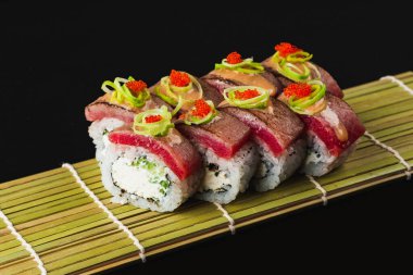 Somonlu suşi ve siyah arka planda sebze.