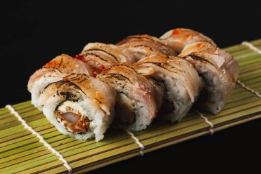 Siyah arka planda somon, yılan balığı ve peynirli suşi rulosu