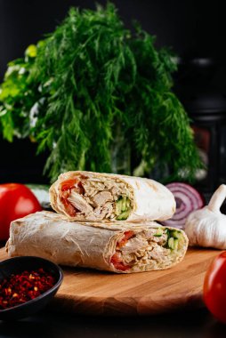 Ahşap bir arka planda sebzeli ve baharatlı ev yapımı tavuk dürümü. 