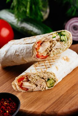 Ahşap arka planda tavuk, sebze ve peynirli ev yapımı shawarma. seçici odak