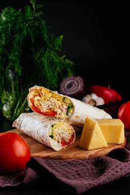 Ahşap arka planda tavuk, sebze ve peynirli ev yapımı shawarma. seçici odak