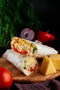 Ahşap arka planda tavuk, sebze ve peynirli ev yapımı shawarma. seçici odak