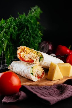 Ahşap arka planda tavuk, sebze ve peynirli ev yapımı shawarma. seçici odak