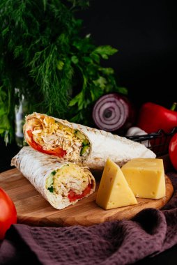 Ahşap arka planda tavuk, sebze ve peynirli ev yapımı shawarma. seçici odak