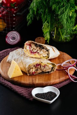 Ahşap arka planda tavuk, sebze ve peynirli ev yapımı shawarma. seçici odak
