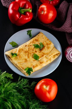 Siyah arka planda peynirli ve etli ev yapımı krepler.