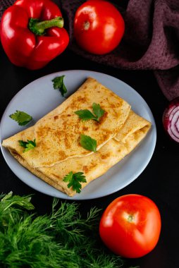 Siyah arka planda peynirli ve etli ev yapımı krepler.