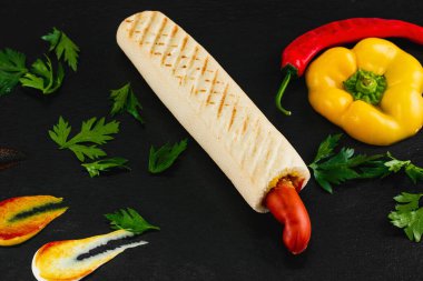 Siyah arka planda sebzeli sosisli sandviç