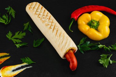 Siyah arka planda sebzeli sosisli sandviç