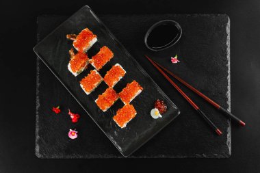 Siyah arka planda kırmızı havyarlı suşi rulosu