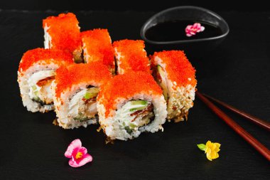 Siyah arka planda kırmızı havyarlı suşi rulosu