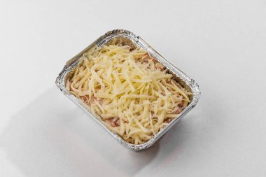 Folyo kutusunda peynirle kaplı pişmemiş lazanya.